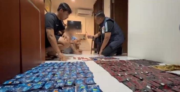 Petugas menyita barang bukti di dalam kamar apartemen.